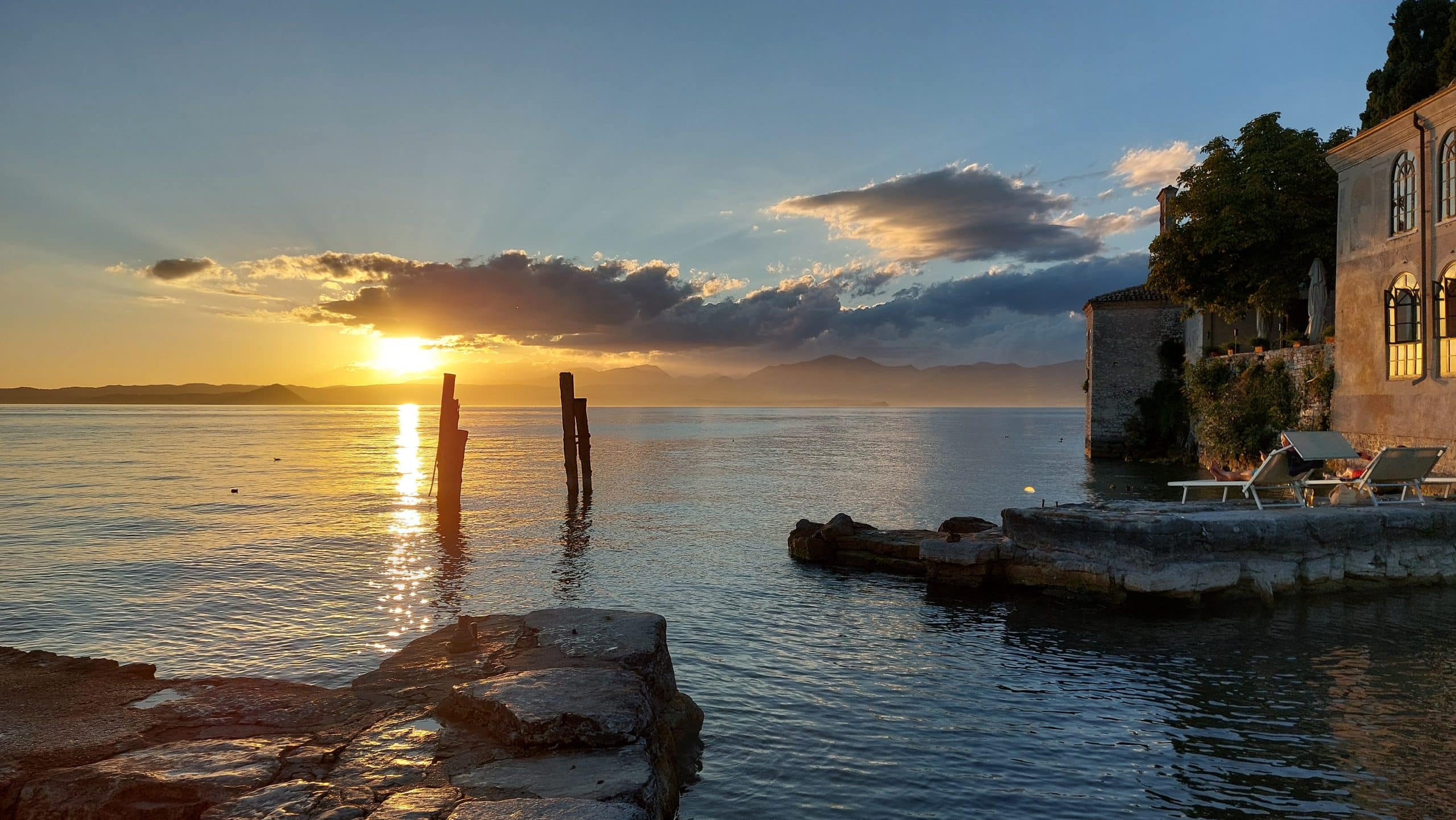 Tramonto sul Lago di Garda con barche ormeggiate e montagne sullo sfondo
