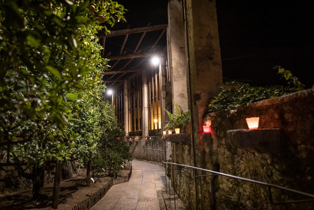 Evening walk through the lemon groves of a historic limonaia in Limone sul Garda, lit by candles