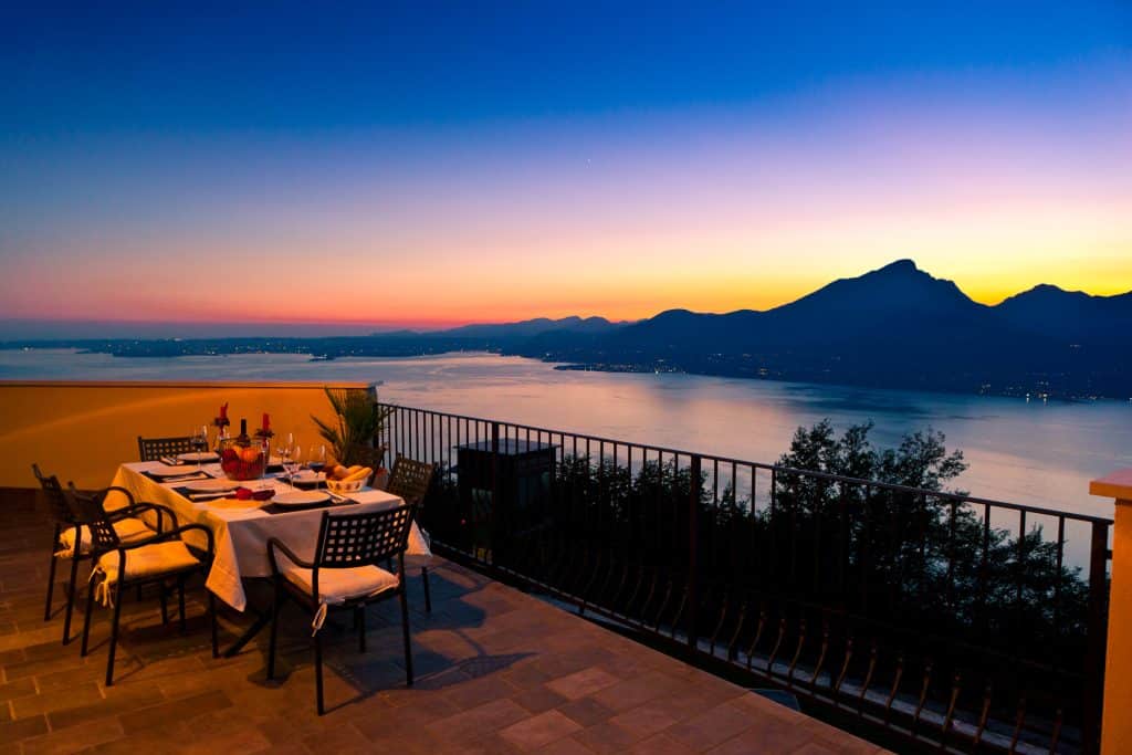 Table set for aperitivo at sunset on a panoramic terrace overlooking Lake Garda