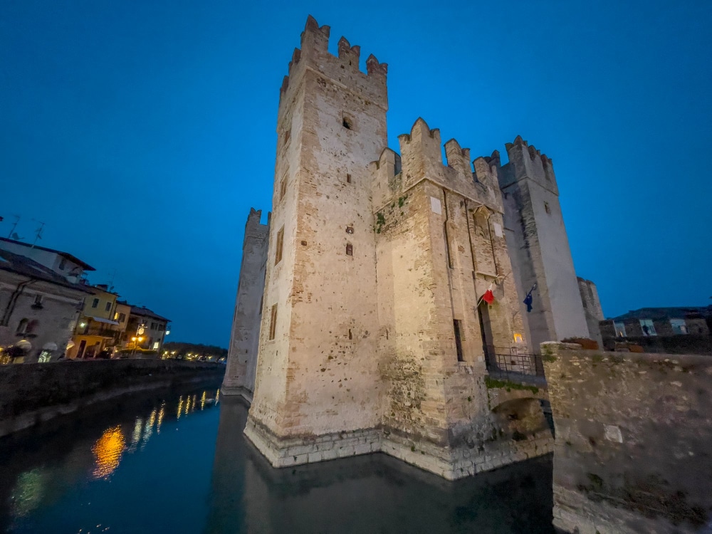 The Rocca Scaligera of Sirmione lit up at blue hour, reflected in the lake